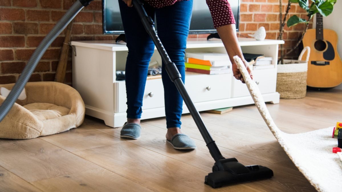 a professional is cleaning floor under carpet with vaccume